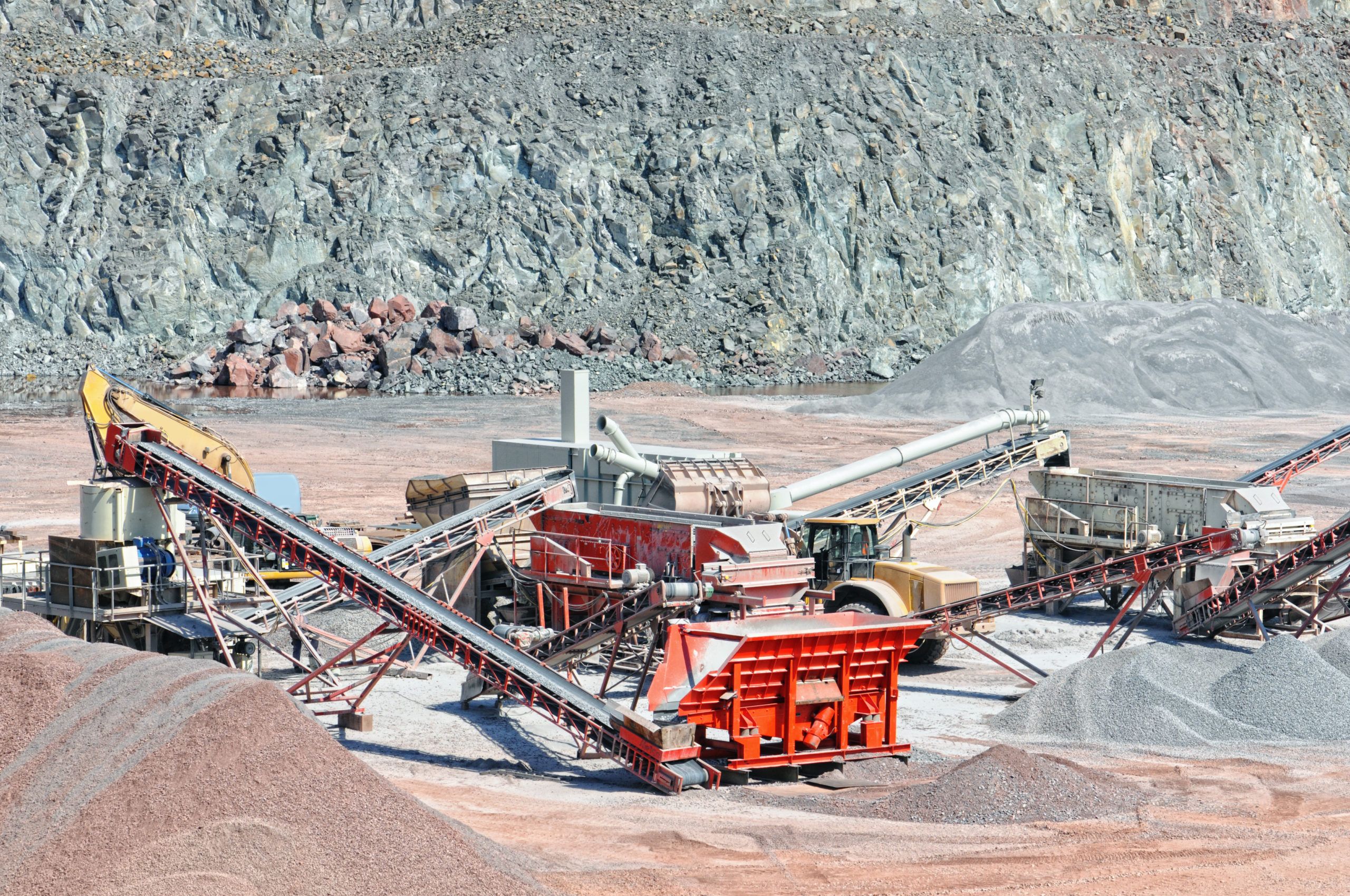 A mineral processing plant with various equipment including conveyors and crushers operating on a rocky site, illustrating the materials handling and infrastructure involved in mineral processing.