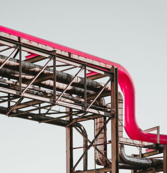 Industrial piping system featuring a red pipe integrated with metal supports, illustrating engineering solutions in civil engineering and system integration for industrial assets.