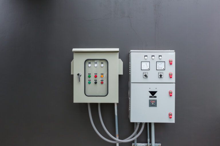 Outdoor electrical enclosures with control panels and circuit gauges mounted on a grey wall