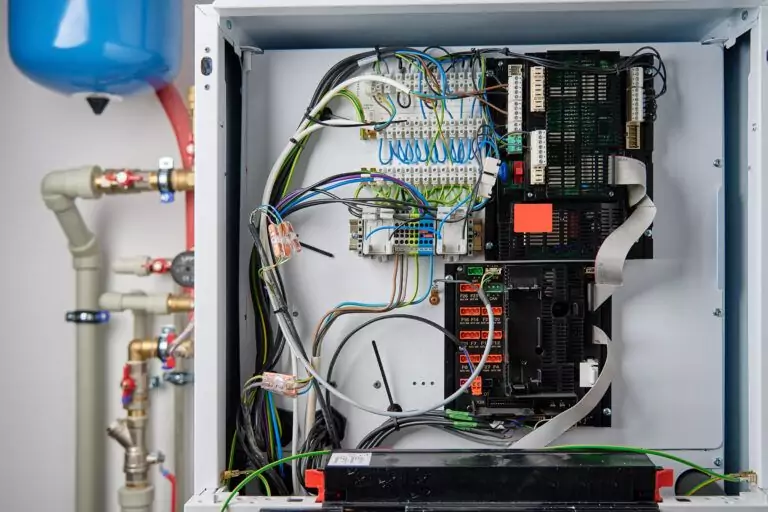 Interior of a boiler control panel showing complex electrical wiring and circuit boards.