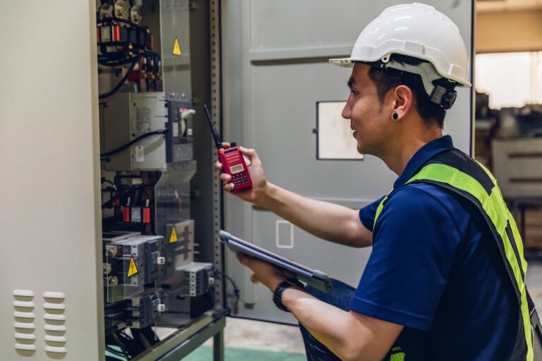 Electrical engineer working in a control room, monitoring voltage levels and system performance.