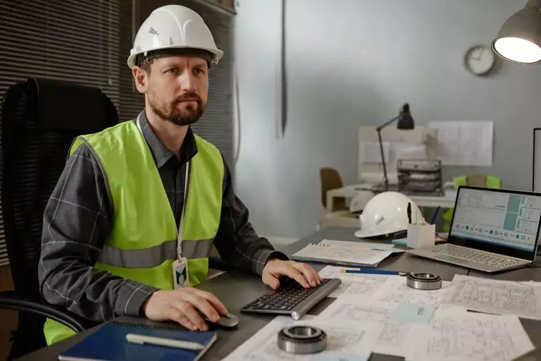 Instrumentation engineer at desk reviewing technical schematics and control system diagrams on computer.