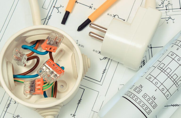 Electrical designer box with connections of electric copper wires and construction drawing of house. Components using in electrical installations. Accessories for engineering work
