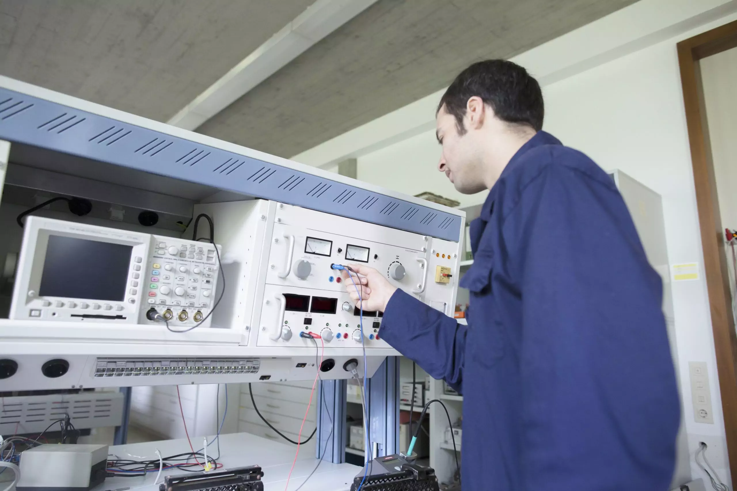 Technician performs high-precision calibration on an electronic instrument using specialized test equipment within a workshop setting, verifying accuracy before field installation.
