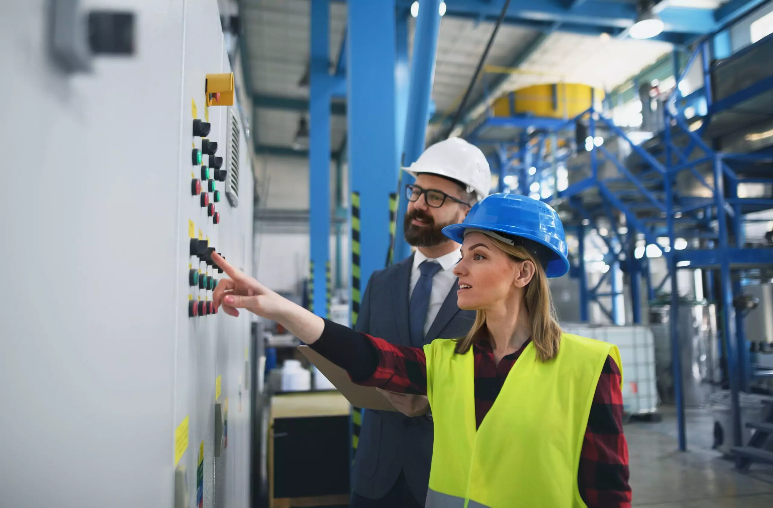 Electrical engineer and technician reviewing industrial control panel to distinguish power systems design from electronics and PLC controls