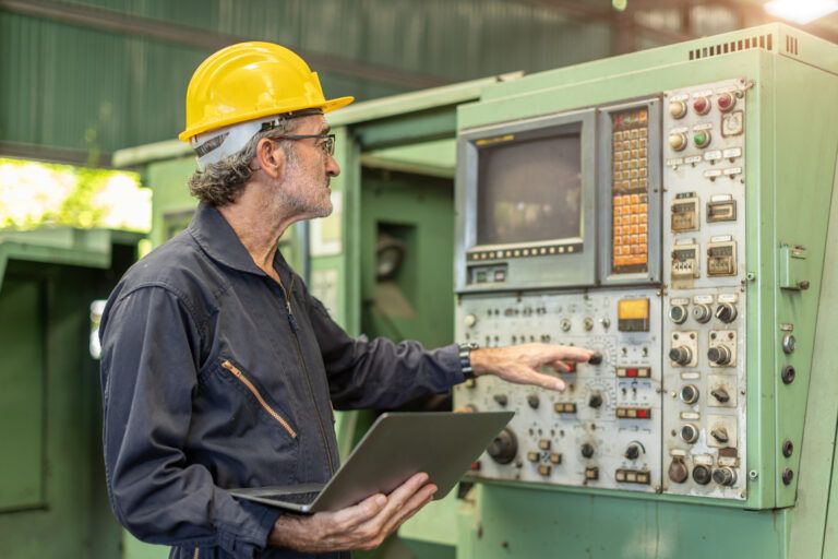 Technician diagnosing industrial control panel with laptop for fault detection, troubleshooting, and root cause analysis