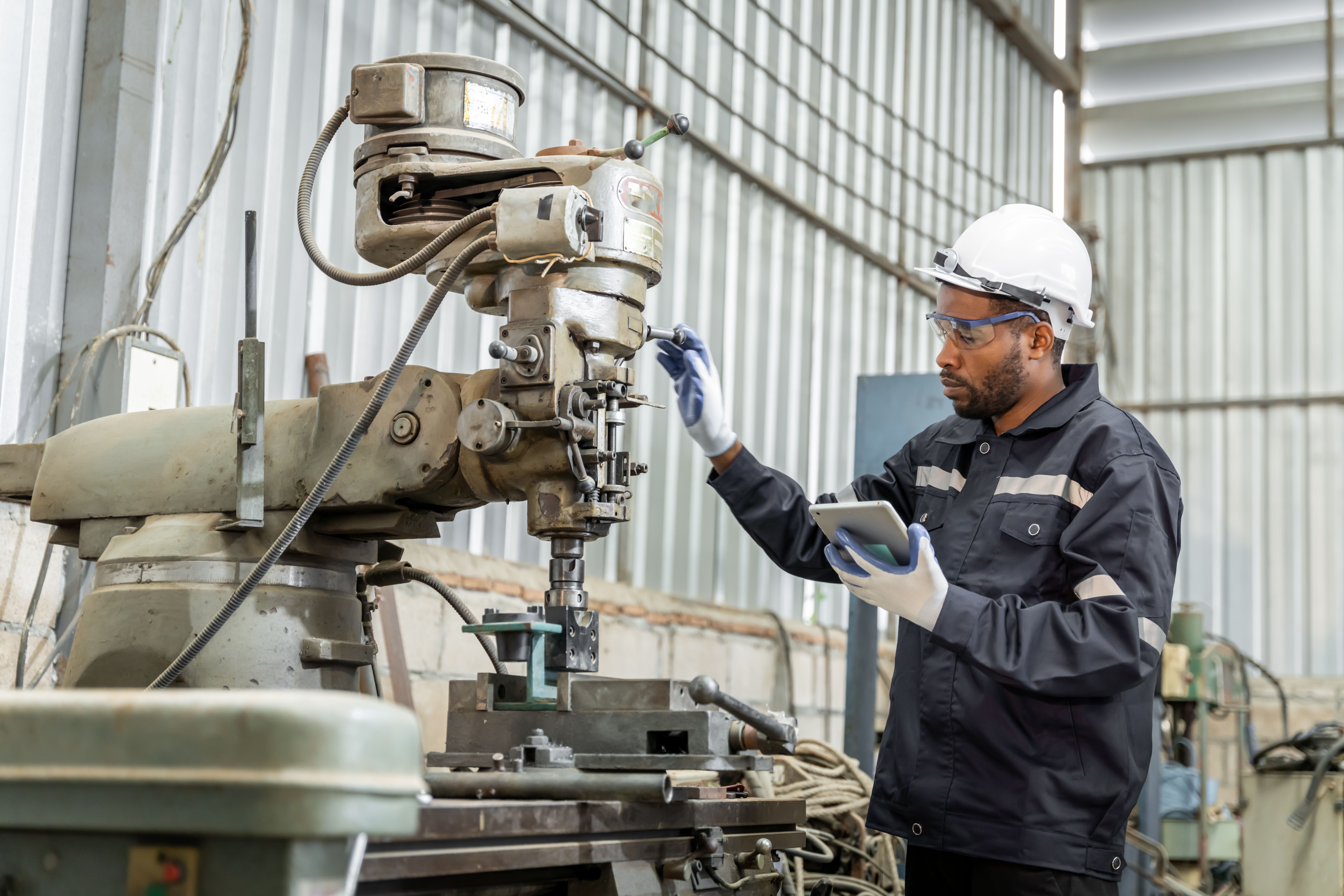 Engineer inspecting industrial machine with tablet for mechanical integrity and early warning signs of failure