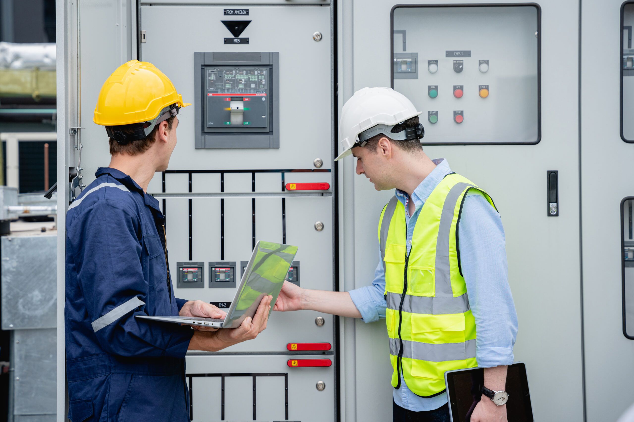 Engineers reviewing power quality data at electrical switchgear for predictive maintenance and early fault detection