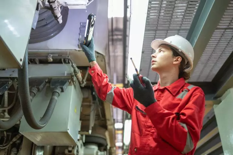 Technician performing predictive maintenance inspection with a handheld analyser on industrial equipment