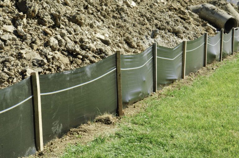 Silt fence with geotextile fabric and wood posts installed along disturbed soil on a construction site